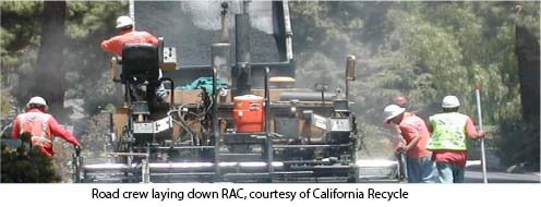 Road crew laying down rubberized asphalt concrete.