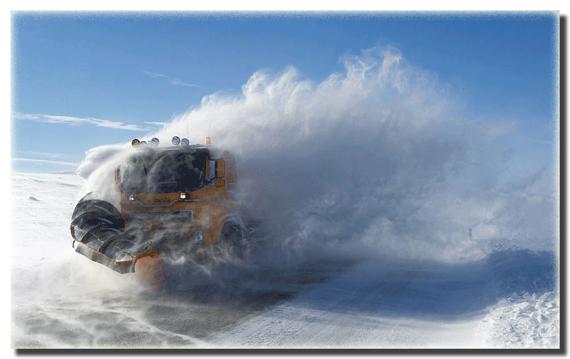 Snowplow in windy conditions plowing the road.